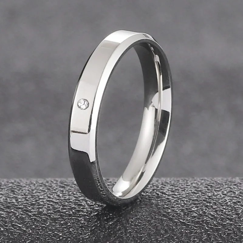 A simple, single-stone, silver-colored couple's ring